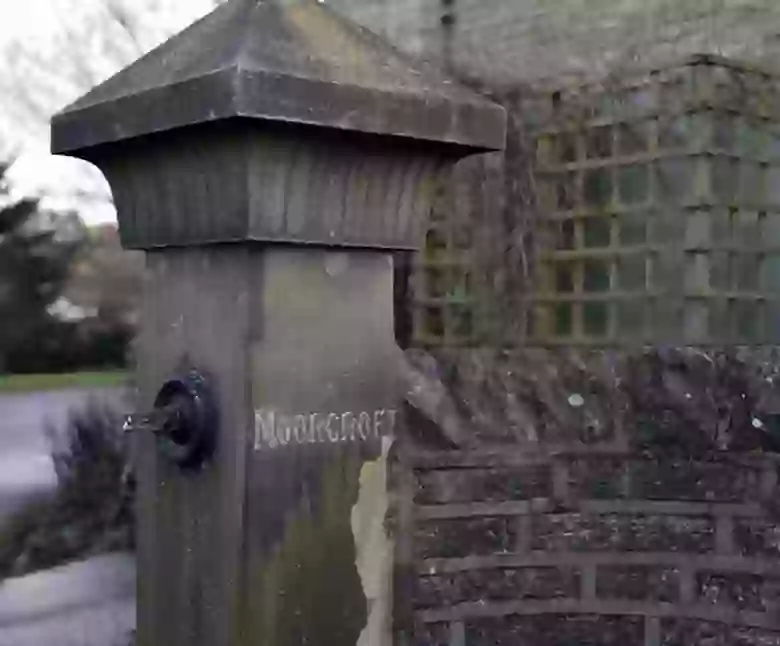 Close-up of the stone gatepost with MOORCROFT engraved on it, marking the studio driveway entrance